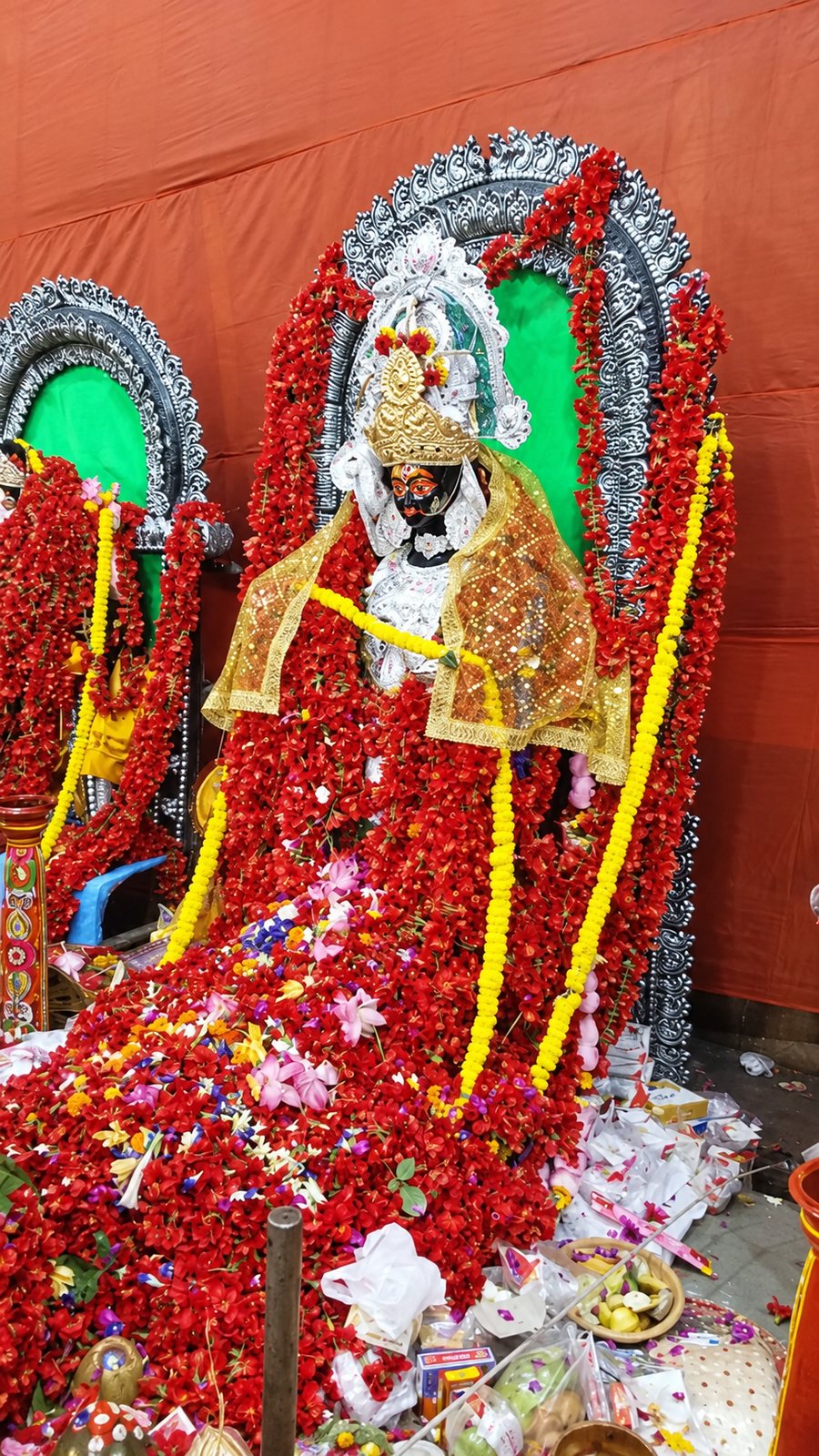 Adi Maa at the Chetla Dasamahavidya Puja — the central idol adorned in red hibiscus garlands with a golden crown and ochre silk, offerings at her feet