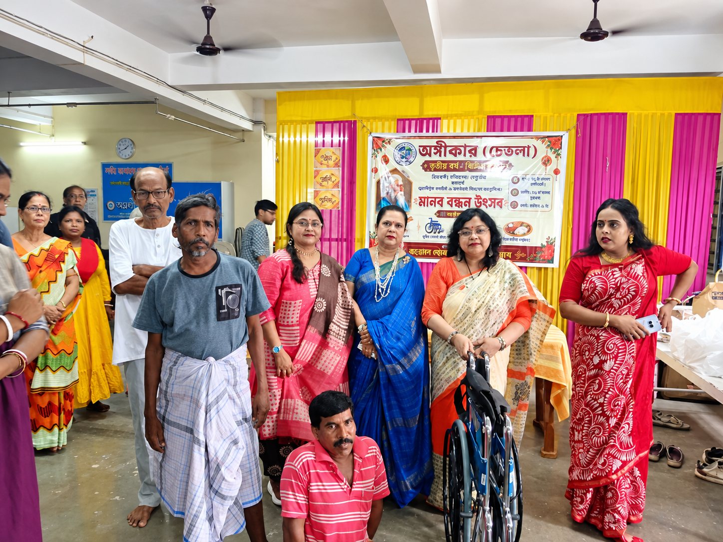 Agnikar, Chetla — volunteers and community members at a year-round social-work event, with a wheelchair presented to a recipient