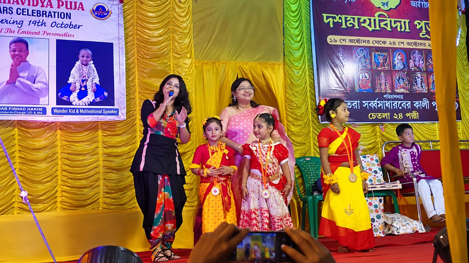 Children in festive dress with medals on the Dasamahavidya Puja stage during the children's competitions